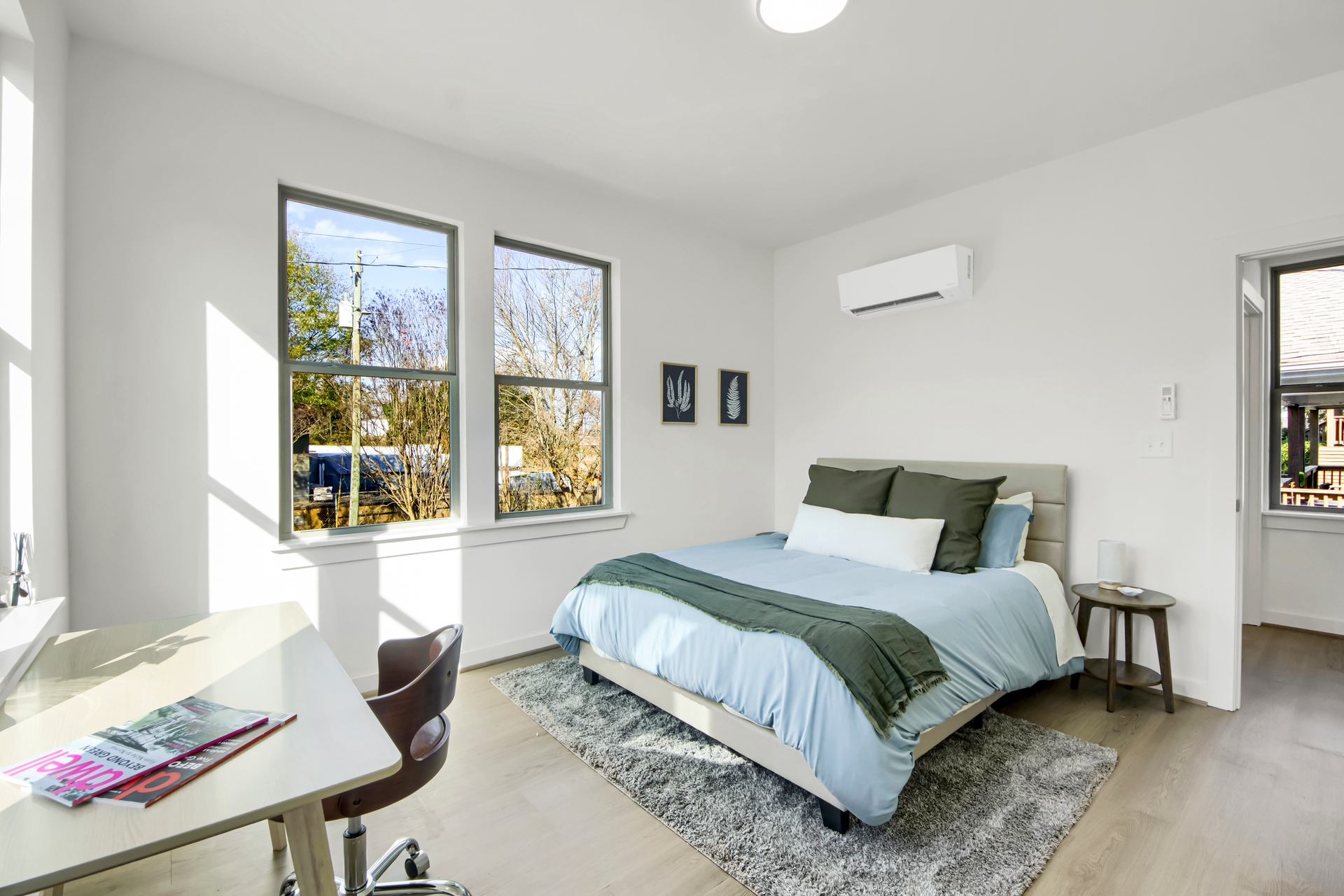Bright bedroom with queen bed, olive and light blue bedding, desk workspace, and natural light from large windows at 1070 Dill Ave