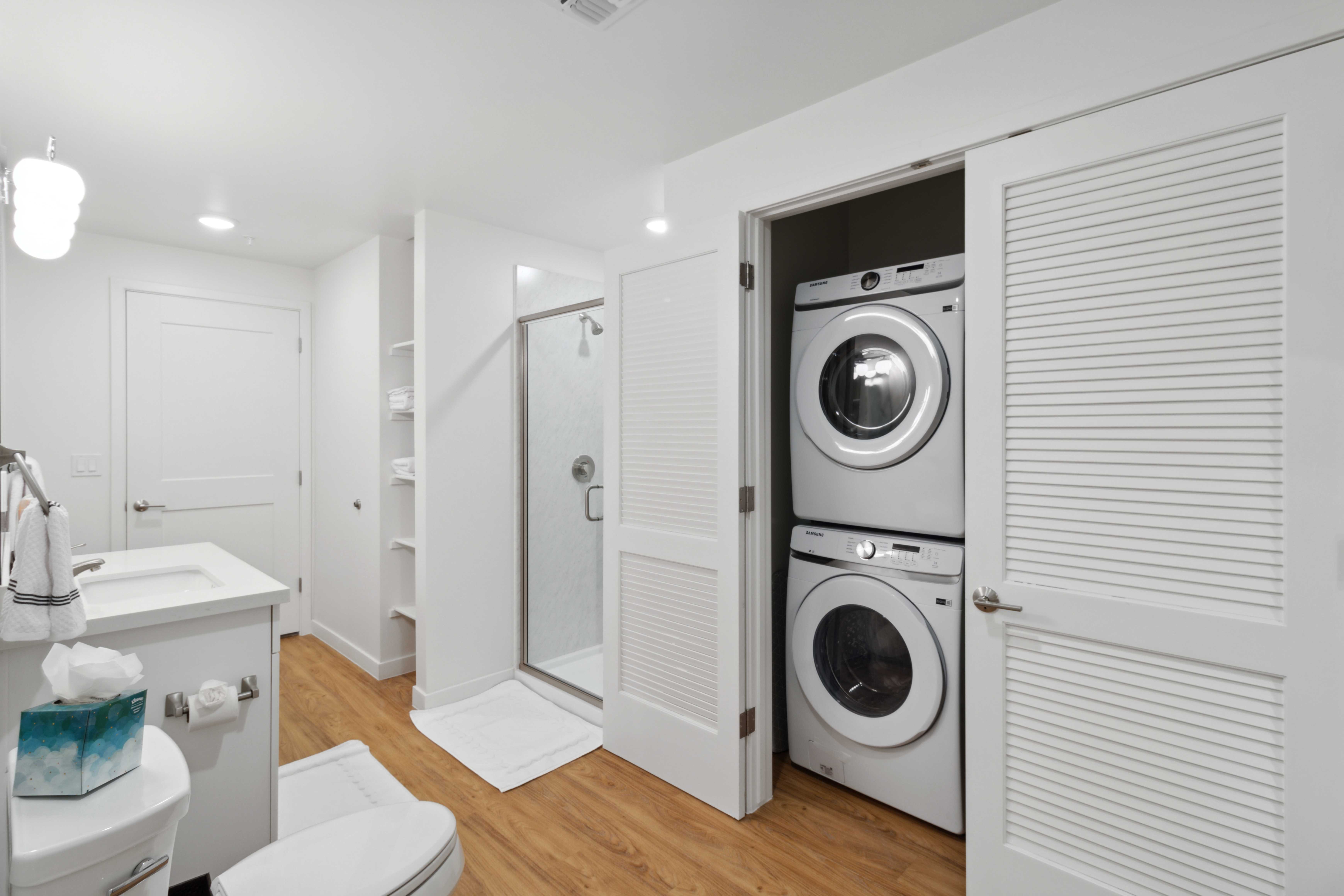 In-unit washer and dryer set tucked neatly beside a modern shower and vanity