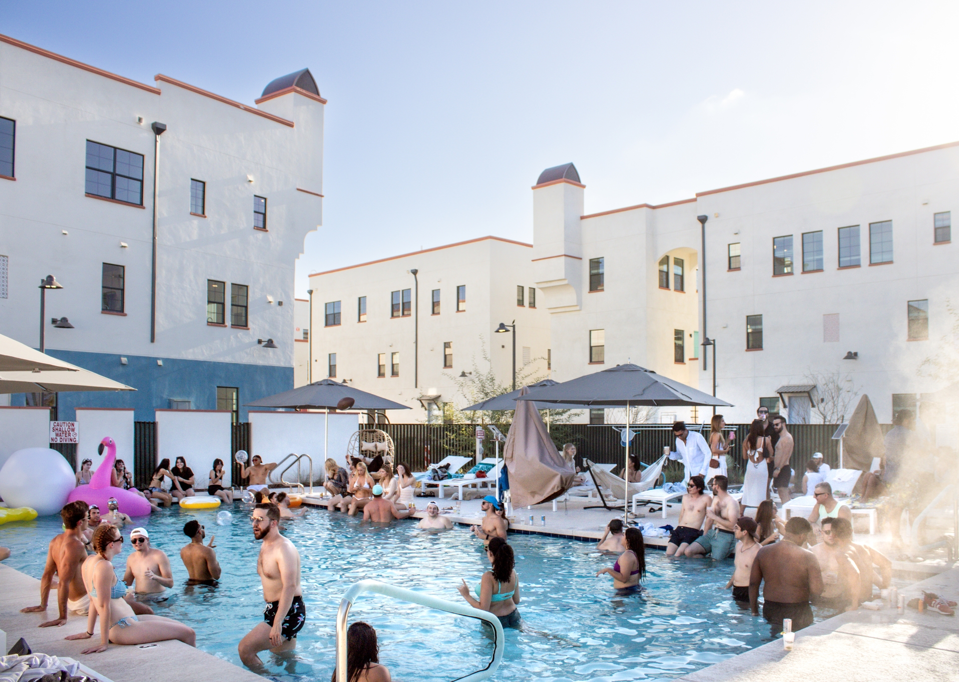 Photo of pool with people swimming and lounge chairs in the background