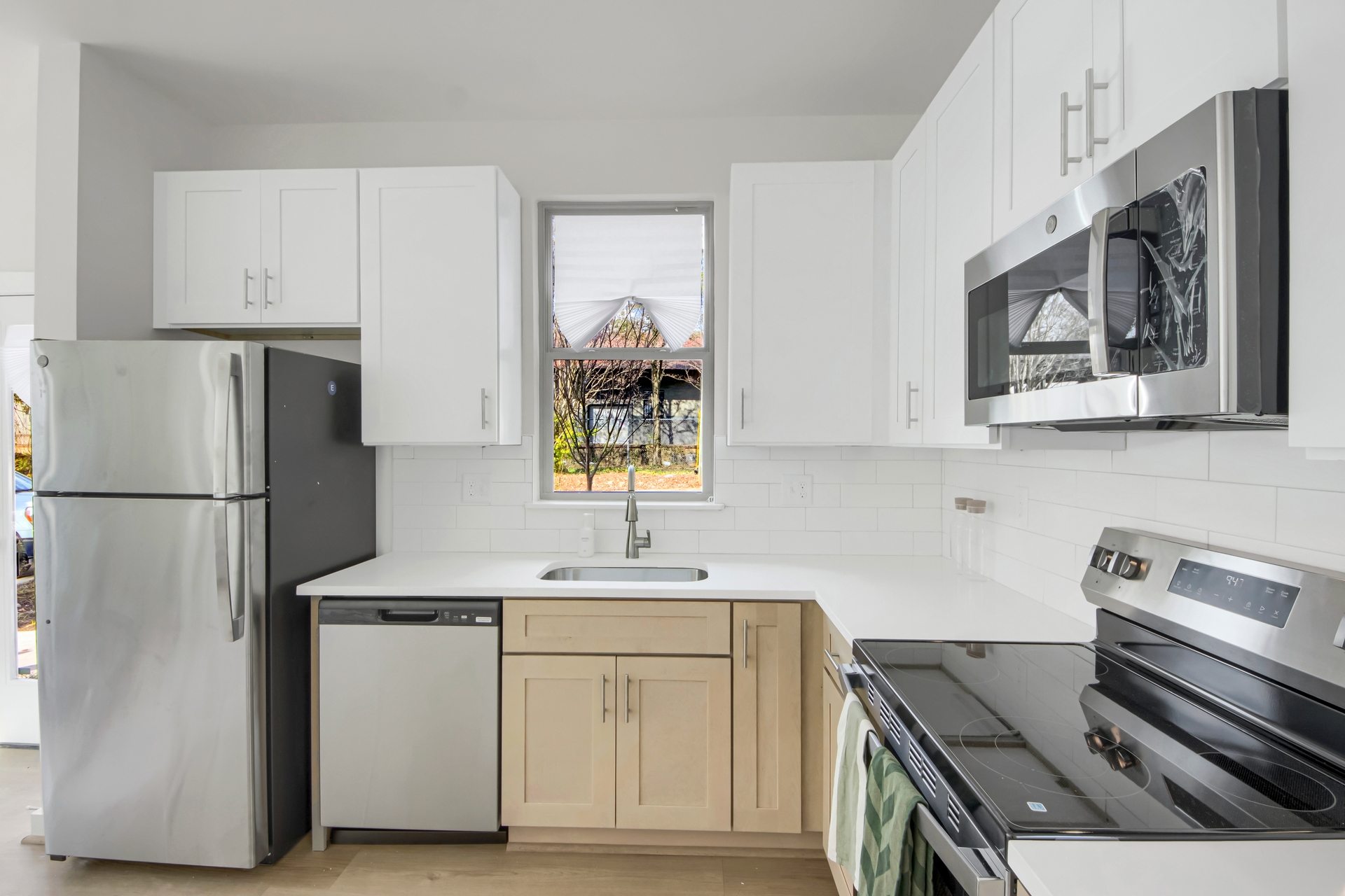 Modern kitchen with stainless steel appliances, white upper cabinets, light wood lower cabinets, and subway tile backsplash at 1070 Dill Ave