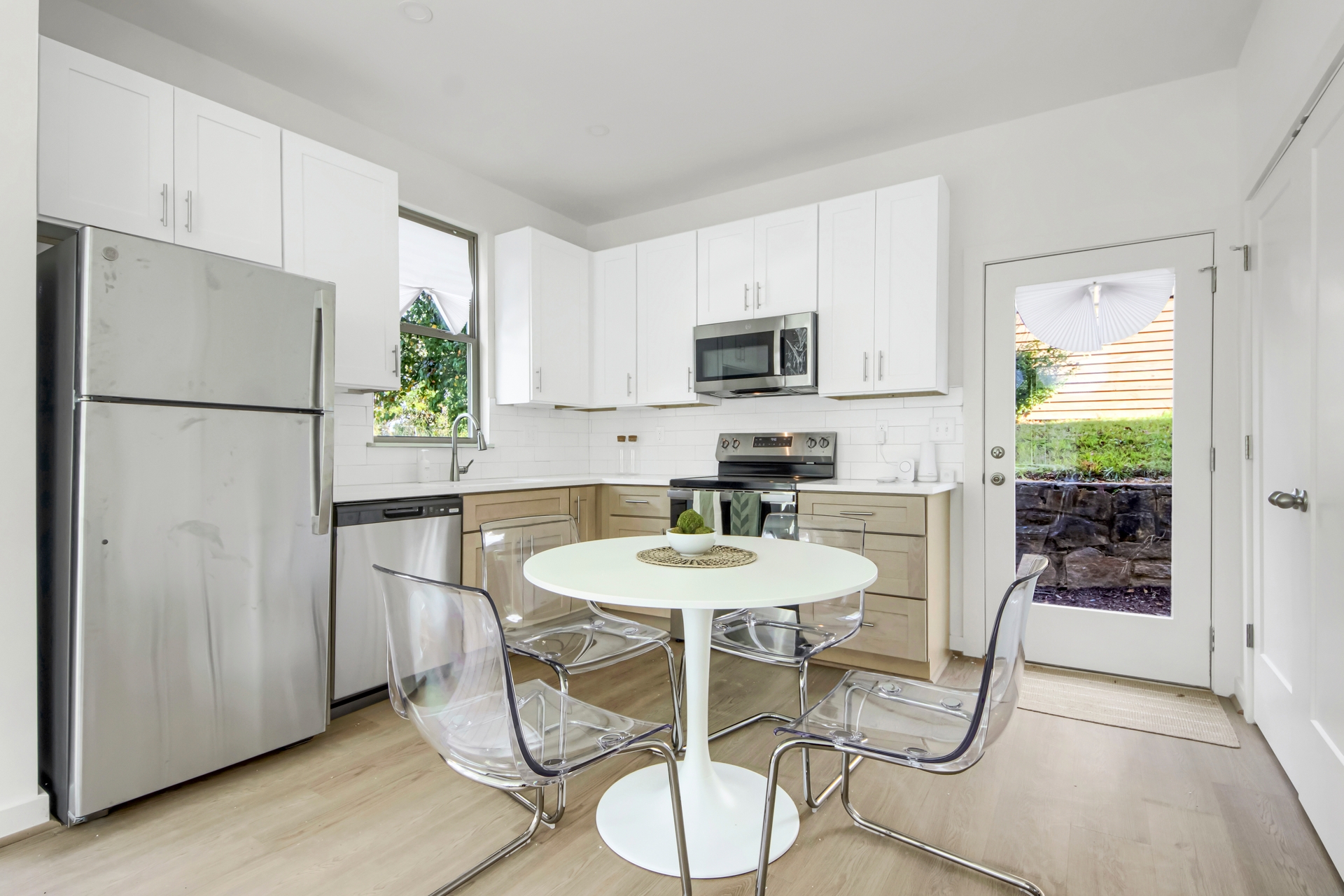 Open kitchen and dining area with white tulip table, clear acrylic chairs, stainless steel appliances, and glass door to patio at 1070 Dill Ave